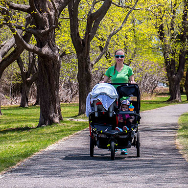 woman walking on a paved trail with a stroller